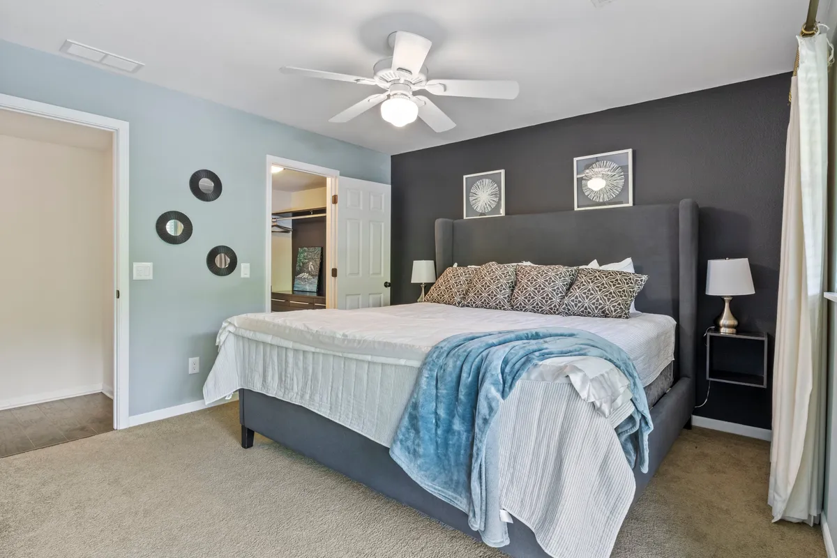 A peaceful bedroom with a king-sized bed, decorative pillows, soothing wall art, and nightstands softly illuminated by lamps. The space feels intimate and ideal for quiet moments.