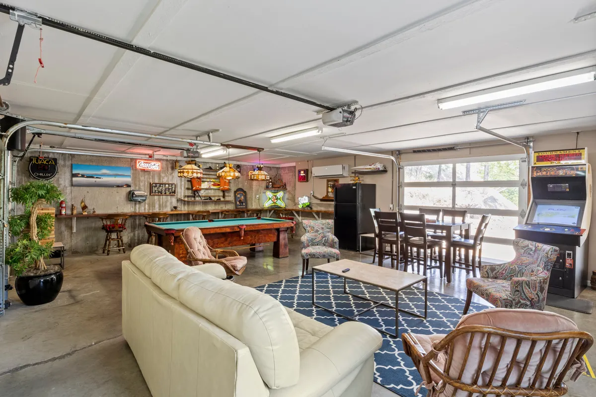 A spacious entertainment room with a pool table, convenient bar area, sofa seating for relaxation, and a dining table for snacks or board games. The welcoming layout invites group gatherings and seamless transitions between different activities.