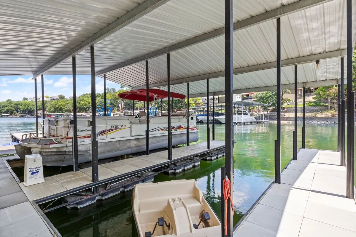Featuring a boat with a red canopy docked at a sturdy platform, this image captures the tranquil lake water and the dock’s recreational potential. The dock appears spacious—ideal for lounging, swimming, and launching water activities such as boat rides and fishing trips.