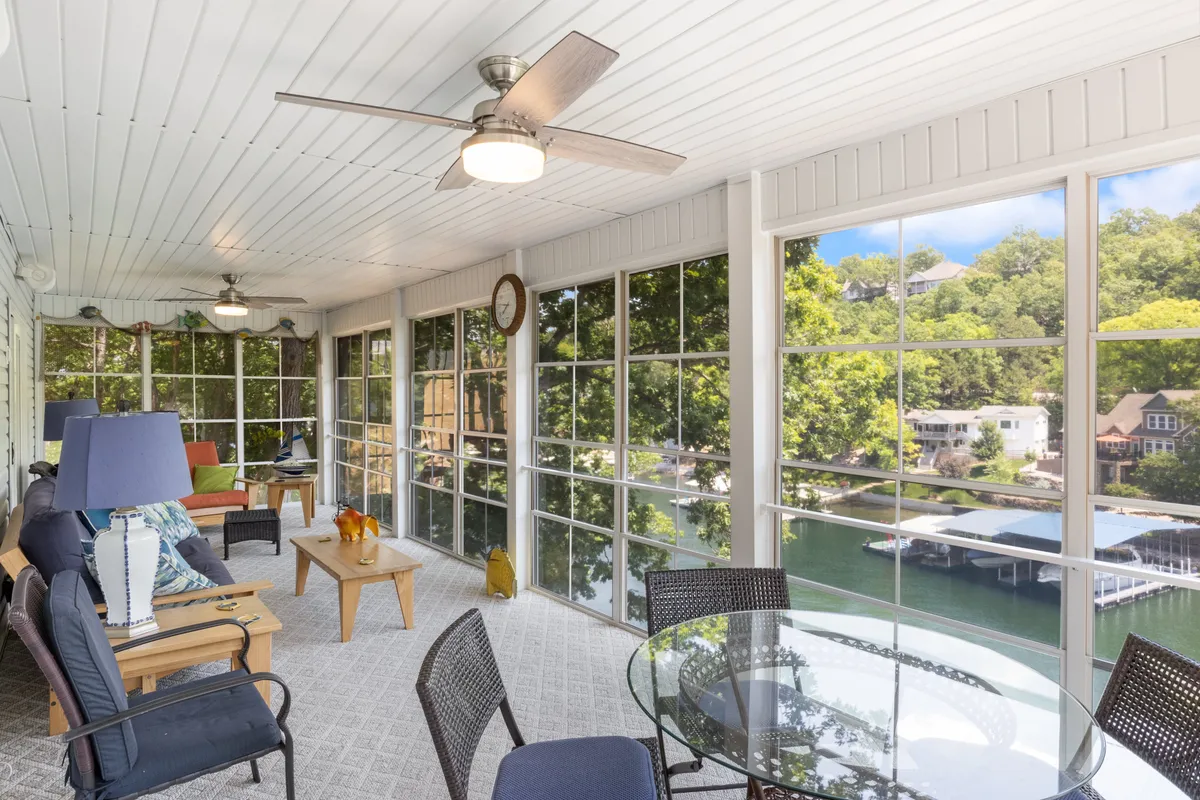 A serene and spacious living and dining area positioned by large windows offering gorgeous water views. Comfortable seating and a dining table invite relaxation and shared meals, while decorative lamps add warmth and ambiance. The windows frame the lake beautifully, tying in the location’s scenic appeal.