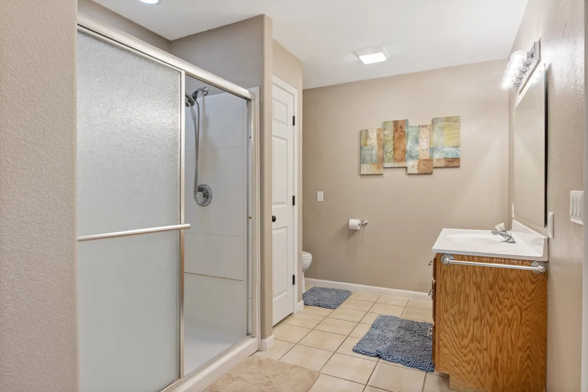A pristine bathroom with a glass-enclosed shower, modern vanity with sink, and elegant wall art. The tranquil setting invites refreshing self-care routines and moments of solitude.